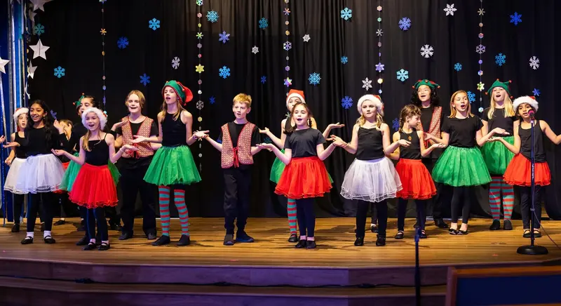 Youth performers in holiday costumes on the Spotlight stage
